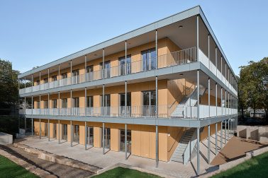 Außenfoto des Rochadegebäudes des Projekts „Lernen im Park“ in Essen, das die modulare Bauweise und die Integration in die umgebende Parklandschaft zeigt.