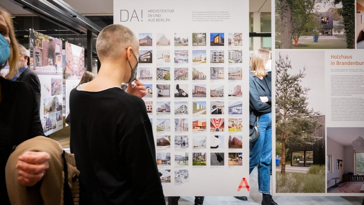 Besucher auf der Ausstellung "da! Architektur in und aus Berlin" vor dem Ausstellungsplakat.
