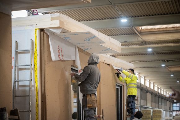 Bauarbeiter und vorgefertigte Holzmodule im Werk für Wohnprojekte von Sehw.