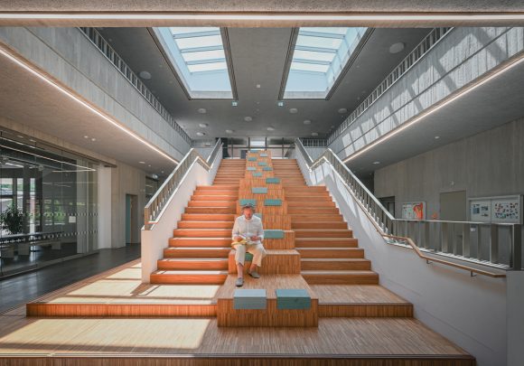 Xaver Egger von Sehw Architektu sitzt auf der zentralen Treppe in der Grundschule am Jungfernsee am Tag der Architektur 2021.